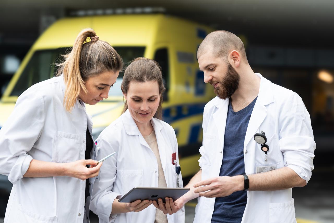 Ärzte stehen vor einer Ambulanz und schauen gemeinsam auf ein Dokument
